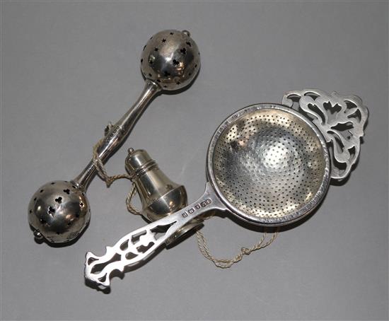 An Edwardian silver babies rattle, a George V silver tea strainer and a miniature silver pepper (3), 2.5 ozs